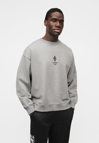 Bluză gri cu guler rotund și umeri căzuți. Prezintă un logo negru centrat pe piept. Textură moale, croială casual.