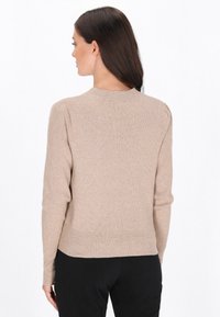 Beige ribbad tröja med rund halsringning och långa ärmar, med en något kroppsryggad nederkant och en jämn textur.