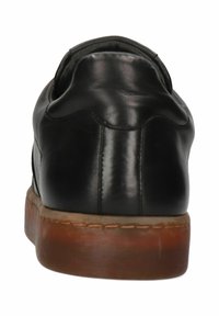 Svart lädersko med avrundad bakdel, med en slät textur, kontrasterande brun gummisula och subtila sömdetaljer längs sömmen.