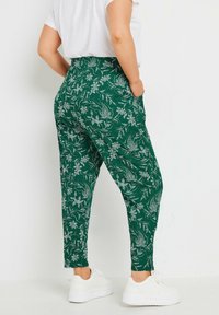 Gröna blommiga byxor med ett strukturerat tyg, med sidofickor och en tapered ben-design. I kombination med vita sneakers.