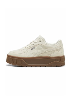 Baskets beige Puma avec semelle épaisse marron, design lacets, texture en daim et logo Puma sur le côté et la languette.