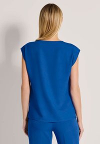 Blaues Kurzarmoberteil mit runder Halslinie, glatter Textur und lässiger Passform. Der Rücken ist einfarbig und hat keine sichtbaren Muster oder Akzente.