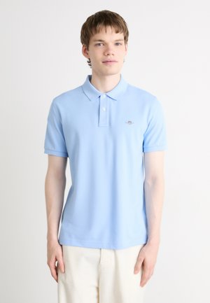 Lichtblauw polo shirt van zachte stof met een klassieke kraag, korte mouwen en een klein logo op de borst. Subtiele textuur, getailleerd ontwerp.