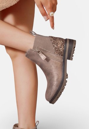 Botte cheville en bronze avec tige texturée, accent scintillant, fermeture éclair sur le côté et semelle robuste. Comprend un détail en maille côtelée et une languette de traction.