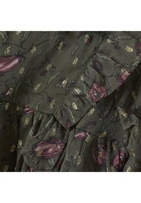 Blommönstrad tyg med rosa tulpaner och guldiga detaljer mot en olivgrön bakgrund. Texturerad med volanger och intrikata sömmar.