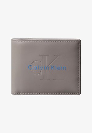 Szara skórzana dwuczęściowa portmonetka z wytłoczonymi inicjałami „cK” i niebieskim logo „Calvin Klein” z przodu.