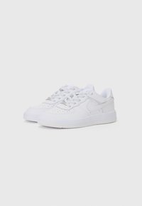 Baskets en cuir blanc avec une texture lisse, boîte à orteils perforée et semelle en caoutchouc. Présente un logo discret et un système de laçage.