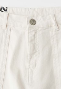 White denim pants waistband with metal button and belt loops, showing detailed stitching and fabric texture.