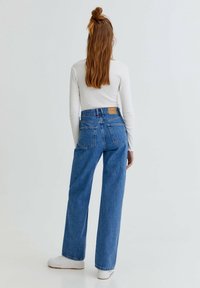 Vaqueros de cintura alta de color azul claro con corte recto, fabricados en denim. Cuenta con una etiqueta de cuero marrón en la parte trasera y en los bolsillos traseros.