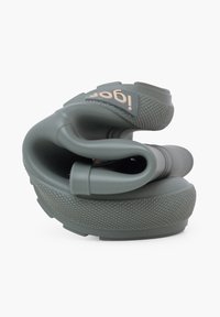 Chaussures en silicone vert flexible avec une semelle texturée, arborant un logo et des courbes lisses pour un ajustement sécurisé. Conception compacte et légère.