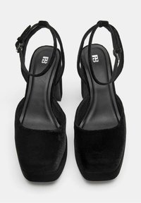 Mustat samettiset korkokengät, joissa on neliön muotoinen kärki, paksu lohkokorko ja nilkkastrappi. Sileä sisävuoraus; vähäiset metalliosat.