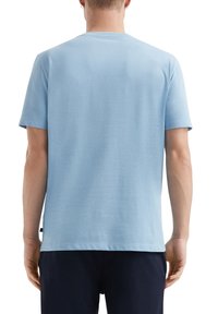 Jasnoniebieska bawełniana koszulka z okrągłym dekoltem, krótkimi rękawami i luźnym krojem. Gładka tekstura z delikatnym połyskiem. Brak widocznych wzorów.