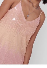 Robe à sequins dégradés roses avec un col en V et des bretelles fines. Tissu texturé avec des sequins brillants de différentes nuances de rose.