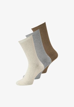 Trois chaussettes montantes côtelées beige, grises et marron disposées en un agencement décalé et superposé.