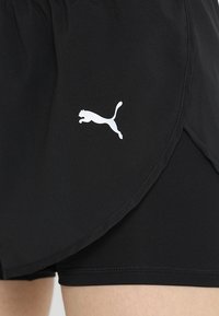 Shorts de sport noirs avec une texture légère et lisse. Dotés d'un logo Puma blanc et d'un design superposé avec des fentes latérales pour plus de mobilité.