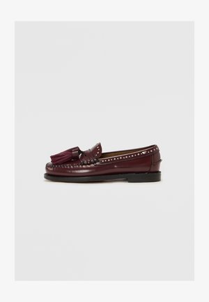 Burgundia nahast loafers, millel on dekoratiivsed tupsud, ja kaeluse ümber on nupud. Ühtlane tekstuur ja klassikaline disain.