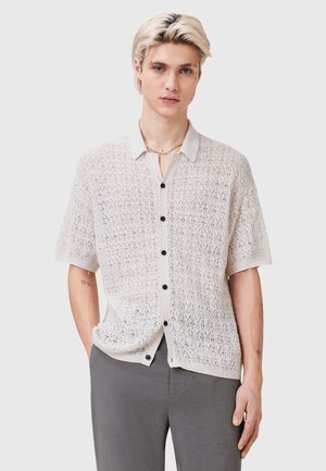 Korte mouwen opengebreid knoopshirt in crèmewit, met een gemêleerd patroon, contrasterende zwarte knopen en een klassieke kraag.