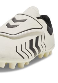 White football cleat with black chevron and stripe patterns, featuring a textured upper and studs on the sole for traction.