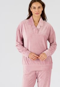 Conjunto de loungewear de terciopelo rosa que incluye una camisa de botones con cuello y textura acanalada, y pantalones a juego. Suave, acogedor y de corte relajado.