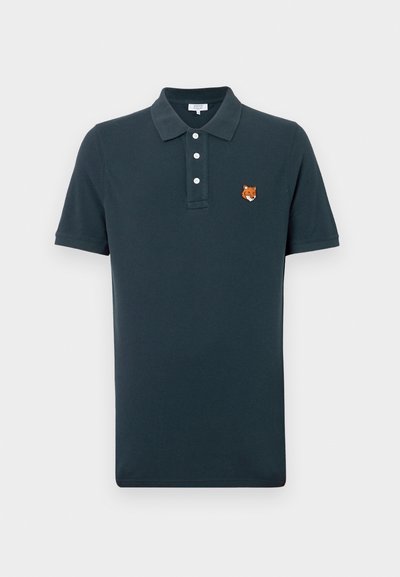 Granatowa koszulka polo wykonana z bawełny, z kołnierzykiem, trzema guzikami i haftowanym logo lisa po lewej stronie klatki piersiowej.