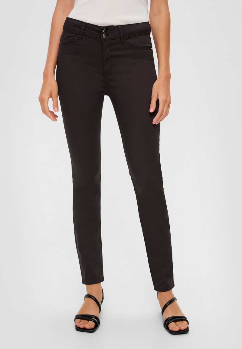Jean skinny noir avec une texture lisse, doté d'une fermeture à bouton, de passants de ceinture et de poches avant. Assorti à des sandales noires à brides.