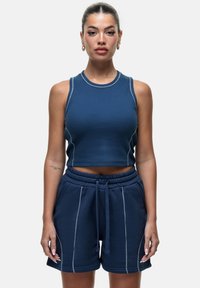Top cropped blu navy con cuciture bianche a contrasto, abbinato a pantaloni corti coordinati con elastico in vita e tasche laterali.