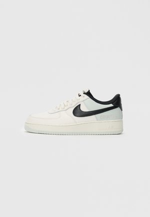 Low-top Nike Air Force 1 sneaker in cream and light gray with black swoosh and Gore-Tex branding on a white background.