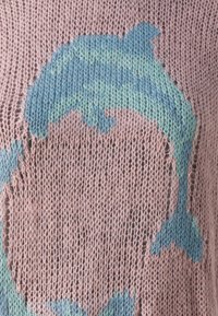 Pull en tricot rose doux avec un motif de dauphins bleus et verts. Présente un tissage lâche et un tissu légèrement texturé.