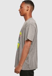 Camiseta de algodón gris de gran tamaño con un gráfico impreso que presenta flores y formas en el frente, mangas cortas y un corte relajado.