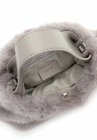 Interno della borsa in pelliccia sintetica grigia con una morbida fodera, tasca con zip e etichetta di marca. Design elegante con bordi lisci e chiusura sicura.