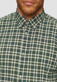 Zielono-biała koszula w kratkę z guzikami, z niebieskimi akcentami, z kołnierzykiem i plastikowymi guzikami, wykonana z lekkiego materiału.
