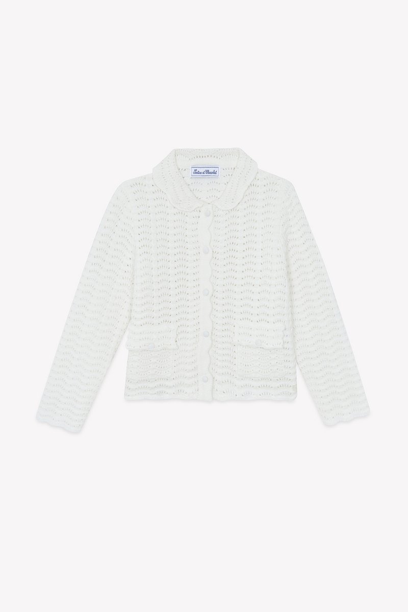 Λευκό πλεκτό ζακέτα με σκαλιδωτό γιακά, κουμπιά μπροστά και δύο μπροστινές τσέπες. Διαθέτει κυματιστό σχέδιο και μακριά μανίκια.