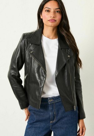 Black leather biker jacket with quilted shoulder accents, silver hardware, zippered pockets, and a fitted silhouette, paired with a white top.