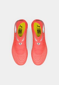 Jasnoróżowe buty sportowe o dopasowanym kroju, teksturowanej powierzchni i siateczkowych detalach. Na wkładce znajduje się logo Puma oraz kod QR.