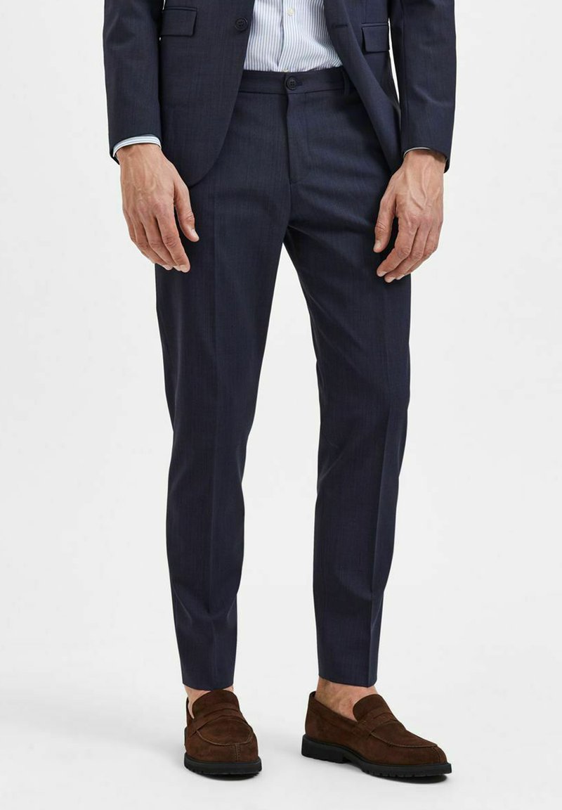 Marinebukser i en tilpasset pasform, med en glat tekstur, subtile striber og forlommer, parret med mørkebrune loafers.