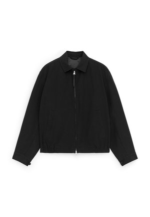 Veste noire légère avec col, fermeture éclair frontale, poches latérales, poignets boutonnés et ourlet élastique, étalée à plat sur un fond blanc.