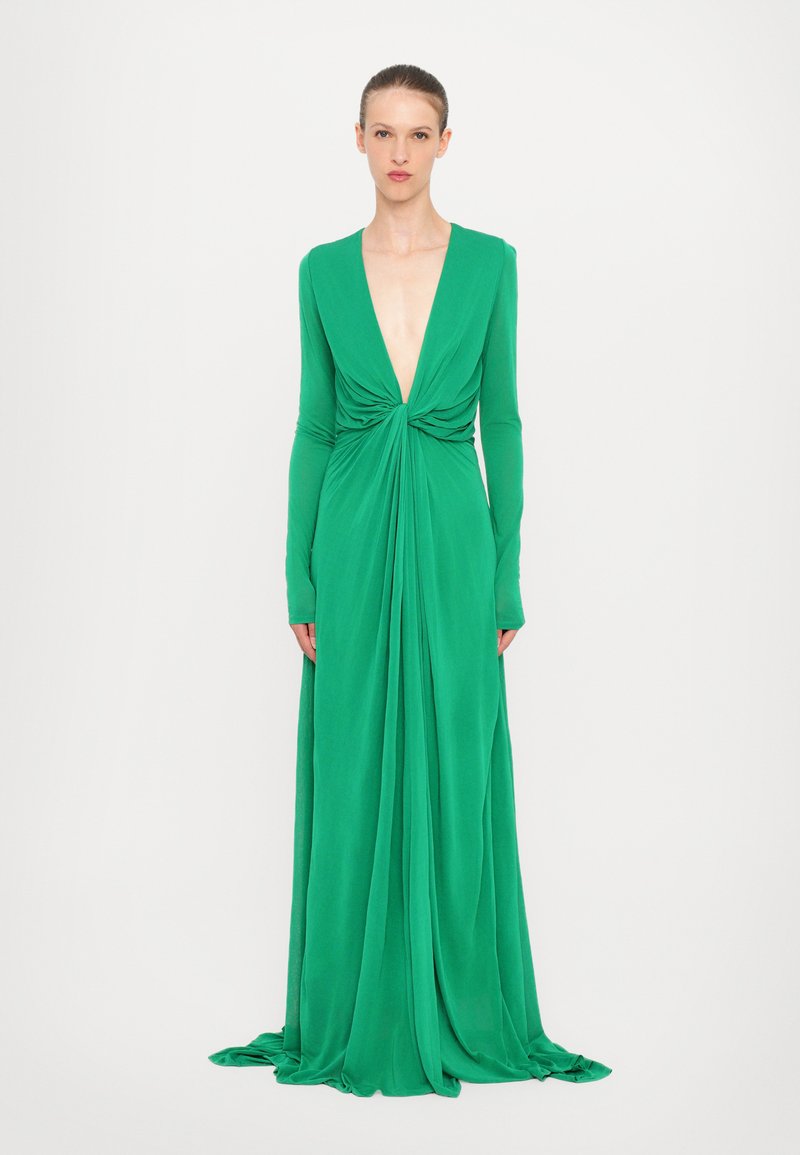 Rochie verde cu mâneci lungi, decolteu adânc în V, realizată dintr-un material fluid, având un nod răsucit la talie și o siluetă până la podea.