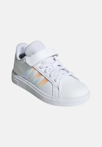Vit sneaker med slät syntetisk ovandel, snörning och kardborrestängning, med tre iriserande ränder på sidan och en gummisula.