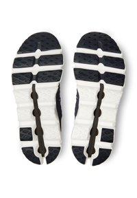 Sportliche Schuhsohle, überwiegend schwarz mit weißen Akzenten. Verfügt über strukturierte Grip-Muster, ein segmentiertes Design und Flexrillen für verbesserte Traktion.