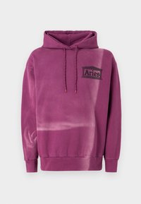 Hanorac violet cu o suprafață moale și texturată. Dispune de un buzunar frontal, glugă cu șnur ajustabil și un logo "Aries" de culoare neagră.