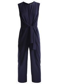 Combinaison sans manches bleu marine avec encolure ronde, jambes larges et ceinture en tissu nouée à la taille.
