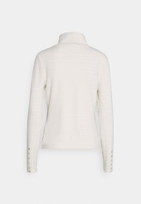 Camisa blanca de manga larga con cuello y un patrón texturizado y acanalado. Presenta cierres de botones en las mangas para mayor detalle.