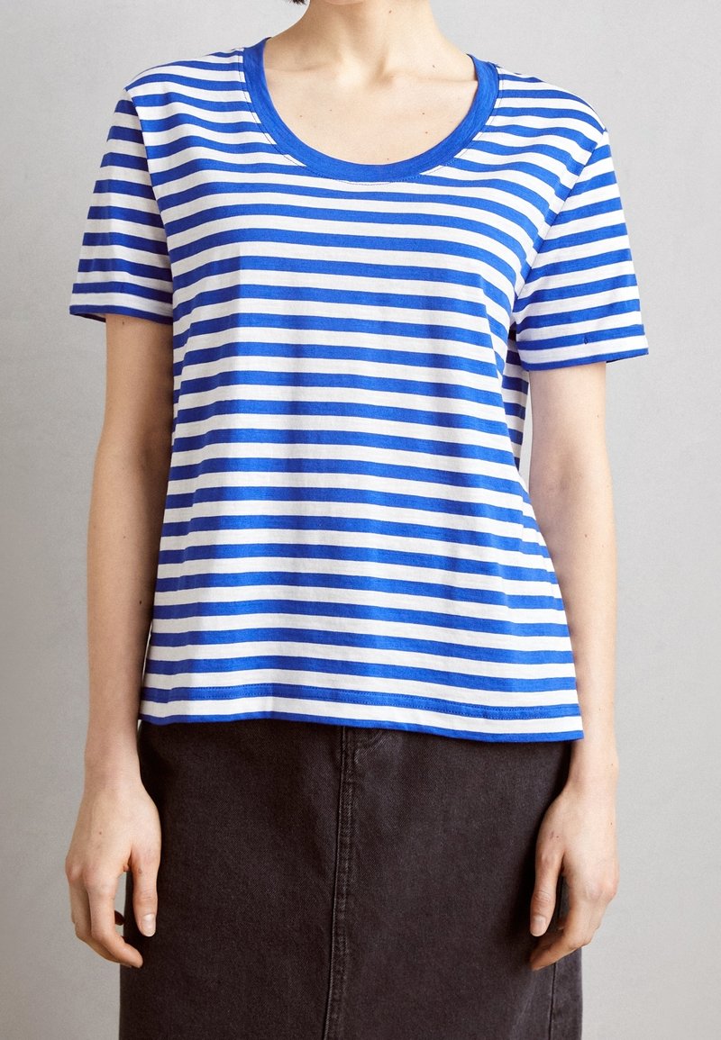 Camiseta de rayas azul y blanca con escote amplio y mangas cortas, confeccionada en una suave mezcla de algodón. Diseño de corte recto.
