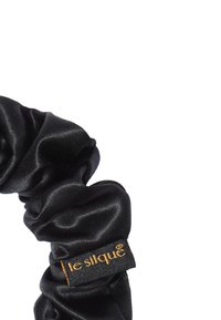 Czarna satynowa gumka do włosów o teksturowanym, marszczonym wzorze i małej złotej metce, ukazująca gładki materiał i elegancki kształt.