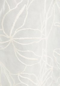 Vit genomskinlig tyg med delikat blommönster som har stora blad och mjuk textur.