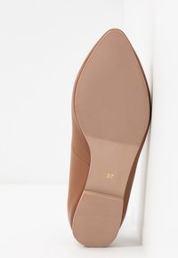 Chaussure plate en cuir marron avec un bout pointu, dotée d'une semelle en caoutchouc texturé et de la taille marquée en or comme 37. Fini lisse avec des accents minimaux.