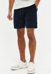 Pantalones cortos de pana en color azul marino con cintura elástica y cierre de cordón, que cuentan con una textura sutil y un detalle de logotipo bordado en el dobladillo.