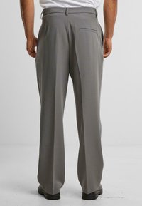 Pantalones en tono gris claro con un diseño de pierna recta, que cuentan con un bolsillo trasero y trabillas para cinturón. Textura suave, apariencia ajustada.
