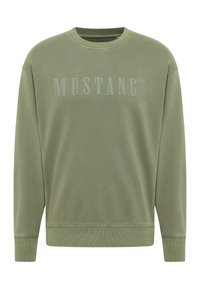 Sweatshirt vert olive en tissu doux, avec un col rond côtelé et des poignets côtelés. Il arbore un logo "MUSTANG" bien visible imprimé sur le devant.