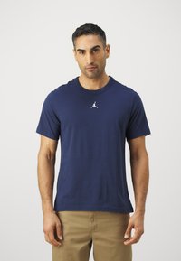 Mørkeblå kortærmet T-shirt lavet af bomuld, med et hvidt Jumpman-logo centreret på brystet og en ribbet halsudskæring.